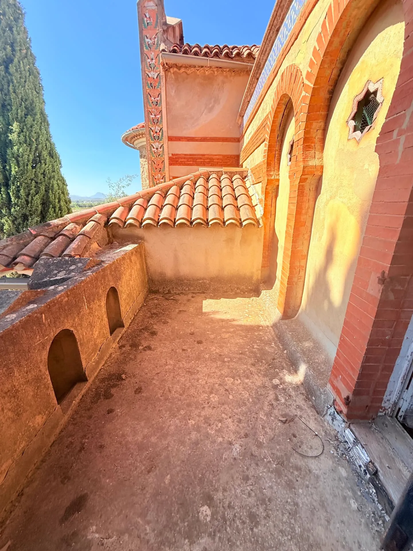 Terrasse extérieure du lot 1.02 du château des Bormettes avant restauration, façade ocre, frises peintes et tuiles